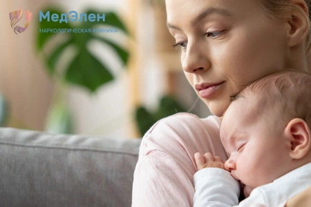 Девушка сидит на диване, держа в руках младенца